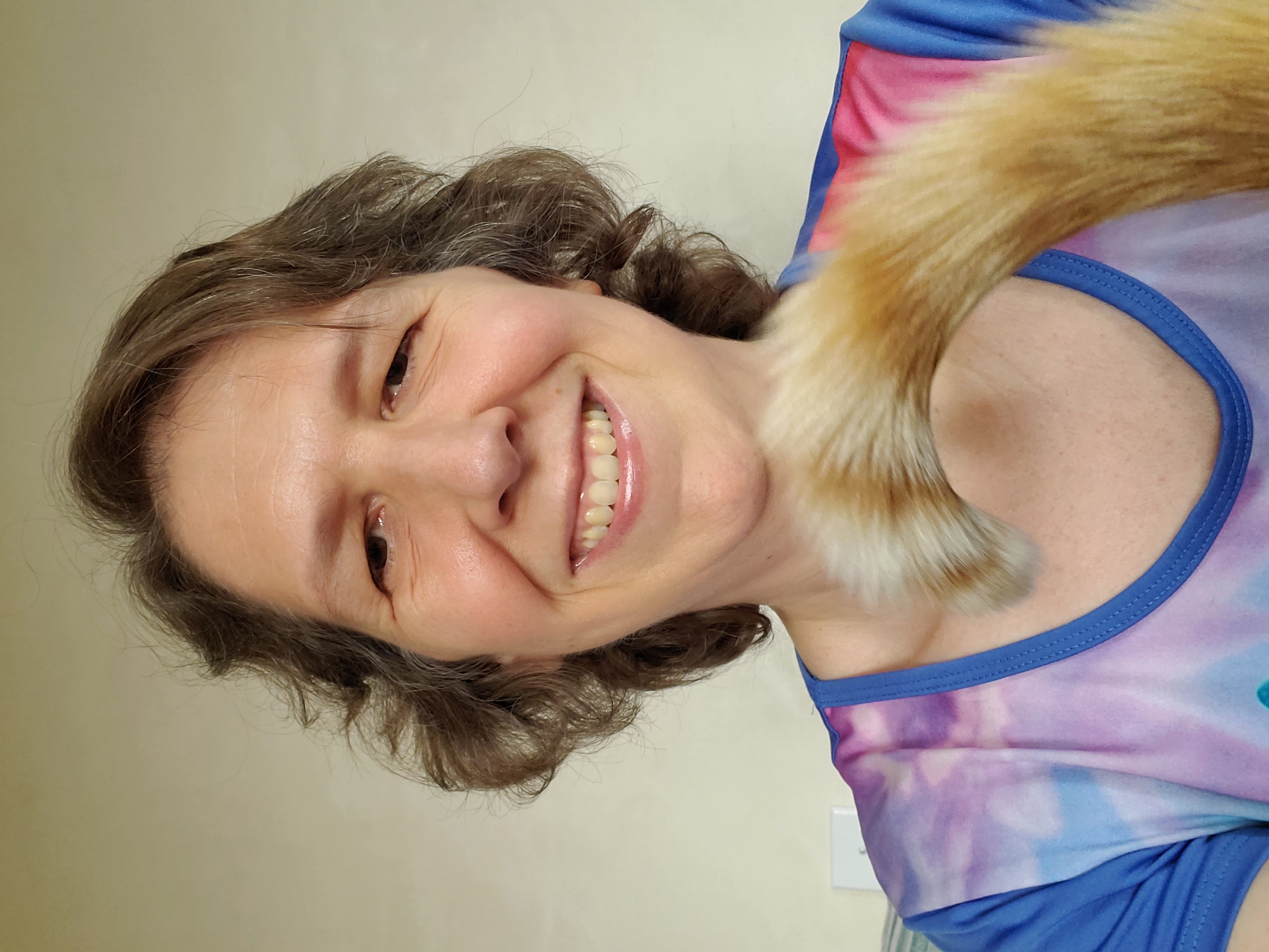 Moriah Williams smiling at the camera, with an orange tabby cat's tail in the foreground